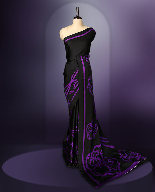 Black colour saree featuring bold floral motifs in deep purple, enhanced with matching striped borders and a contemporary patterned pallu, paired with a coordinating blouse.