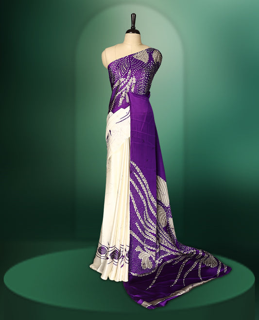 Purple colour Semi Modal saree featuring artistic abstract prints across the body, beautifully contrasted with Off  White highlights, complemented by a bold patterned pallu, and paired with a matching blouse