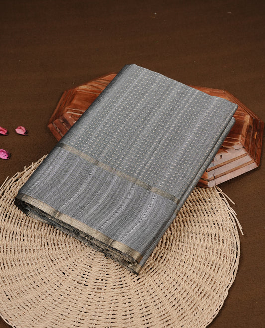 Grey colour semi tussar silk saree featuring elegant gold zari dotted stripes across the body, enhanced with a rich zari woven border. Comes with a matching blouse piece.