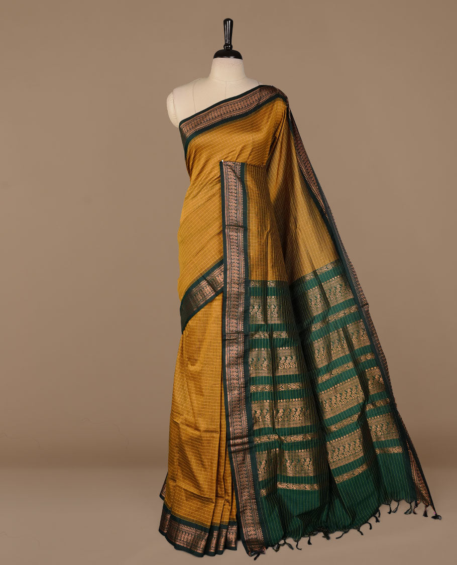 Mustard colour kalyani cotton saree featuring gold zari check pattern on body, complemented by green colour with Antique zari border, paired with matching blouse piece.
