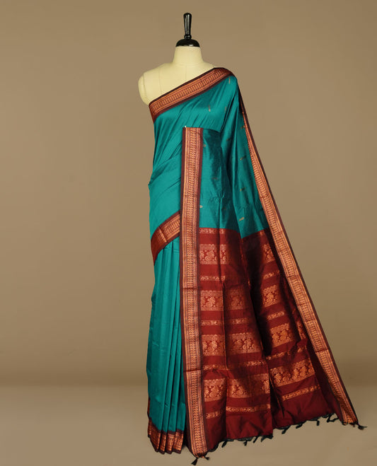 Teal colour kalyani cotton saree featuring antique zari motifs on body, complemented by Maroon colour with Antique zari border, paired with matching blouse piece.