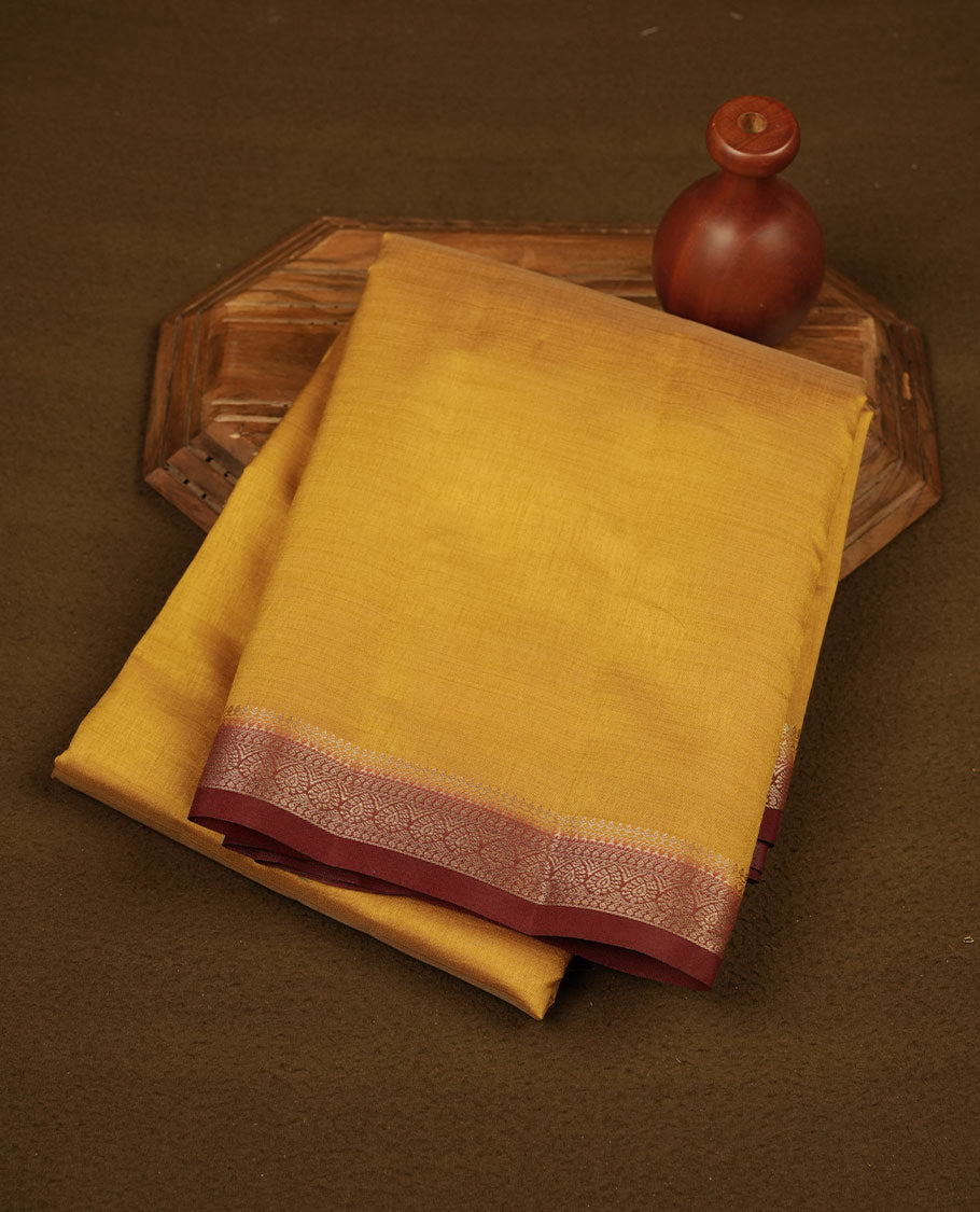 Gold colour semi tussar saree featuring elegant plain body, contrast maroon colour gold zari border and comes with matching blouse piece.