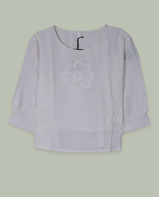 White three-quarter sleeve top with round neckline and tonal crochet floral appliqués placed at the center front and near the hem.
