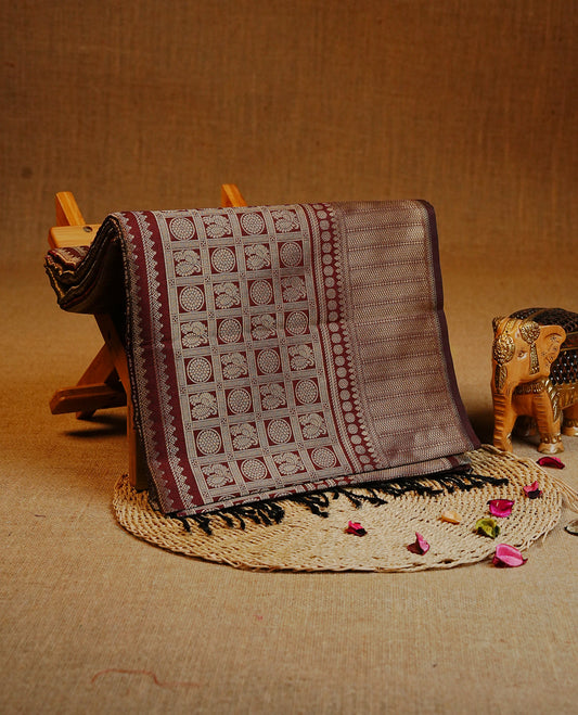 Chocolate brown color Semi Soft Silk Saree Featuring Gold Zari Checks With Delicate Motifs And Stripes Across The Body, Enhanced With A Self Coloured Gold Zari Border, And Paired With A Matching Blouse Piece.