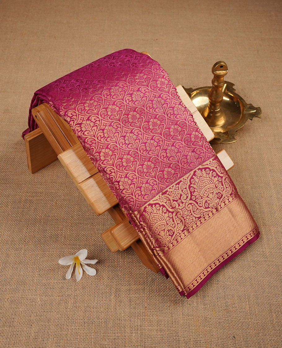 Magenta pink colour kancheepuram silk saree featuring floral zari jacquard on body with traditional border, paired with matching blouse piece.