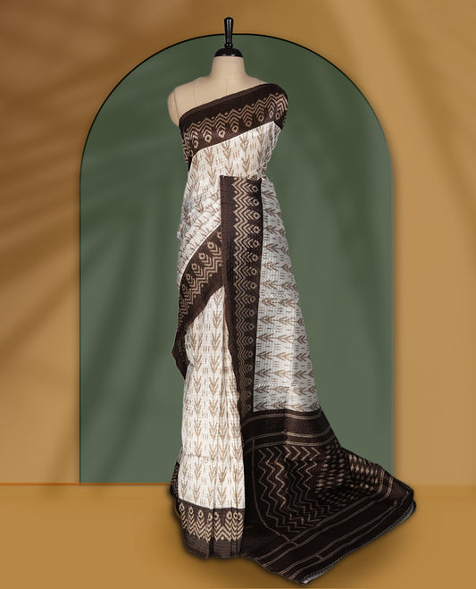 Classic off white colour saree adorned with intricate brown tribal motifs and rich woven patterns on the pallu and border & Paired with matching blouse.