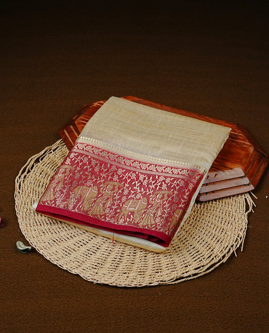Light gold tussar saree featuring Elegant plain body, complemented by contrast Maroon colour with Gold zari Floral kodi with Women & Cow Pattern border, comes with matching blouse piece.