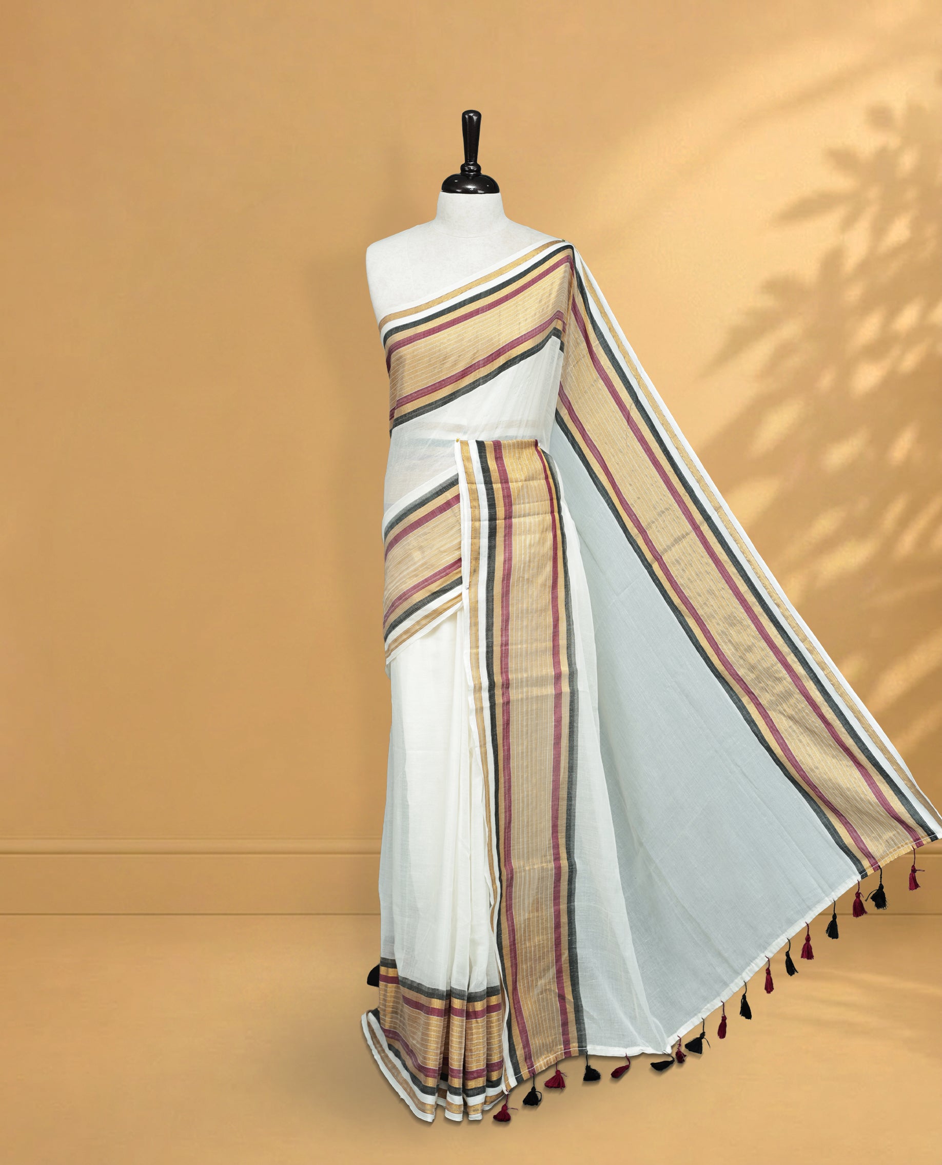 Off White Colour Mul Cotton Saree featuring Elegant Plain Body, Contrast Gold, Wine & black Border and Tassels Onam inspired charm.