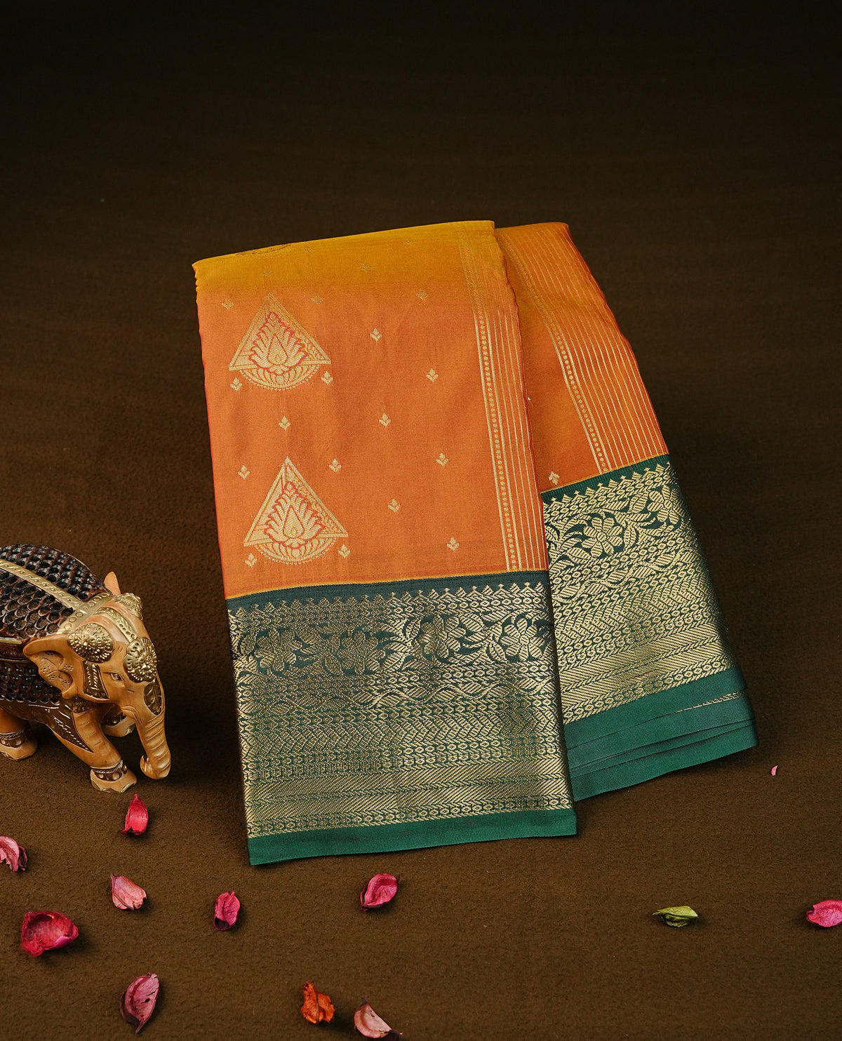 Rusted orange colour semi wedding silk saree featuring gold zari with motifs on body,contrast bottle dreen colour with traditional border on body, rich pallu comes with matching blouse piece
