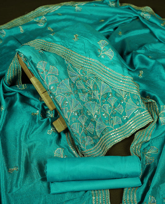 Teal colour churidar material with subtle mirror and thread embroidery, finished with delicate border detailing and paired with a matching plain bottom and dupatta.