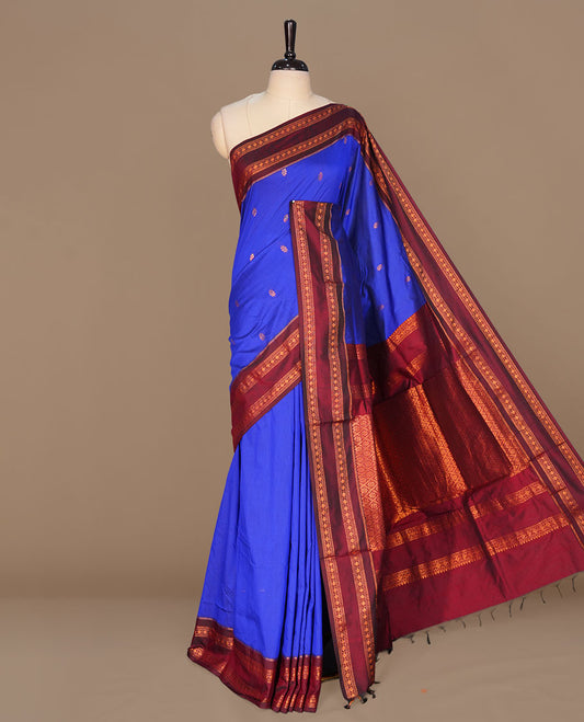 Navy blue colour kalyani cotton saree featuring gold zari motifs on body, complemented by contrast maroon color with copper zari pattern border , paired with matching blouse piece.