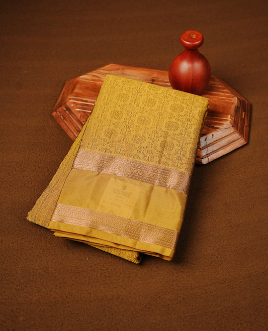 Mustard Yellow Colour  Semi Soft Slik  Saree Featuring An Elegant Self Floral Woven Body, Enhanced By A Traditional Rose Gold Zari Border And Rich Pallu, Paired With A Matching Blouse Piece.