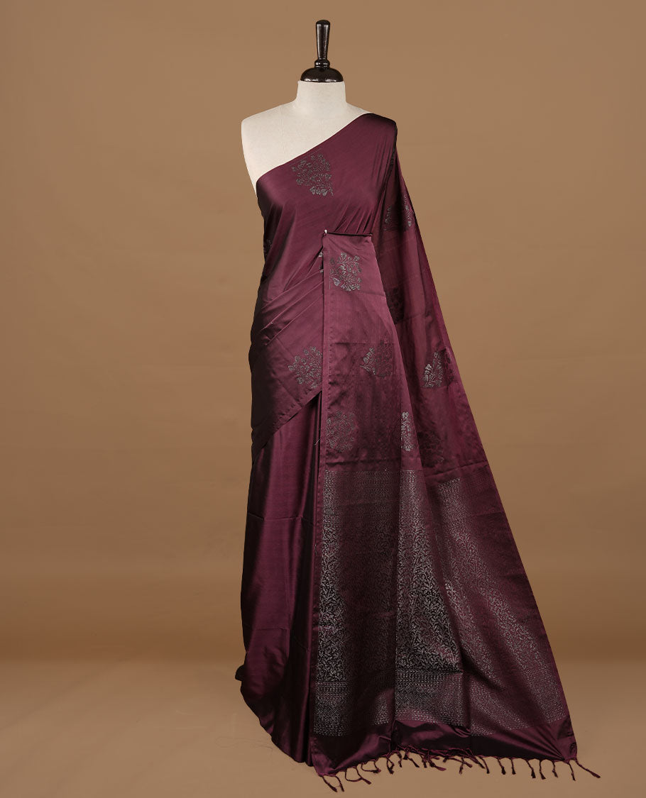 Burgundy soft silk saree features a sleek borderless design with intricate antique zari motifs, flowing into a seamless self colored pallu and a matching blouse piece.
