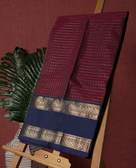 Maroon colour pure Kanchi cotton saree featuring with delicate golden checks on body, paired with a contrasting navy blue zari woven border & Includes a matching blouse piece for a complete look.