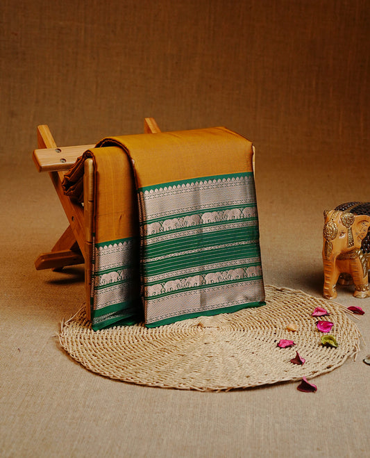 Mustard Colour Kancheepuram silk saree featuring gold zari motifs on body, highlighting Gold zari Elephant Traditional On contrast Green border, paired with Matching blouse piece.