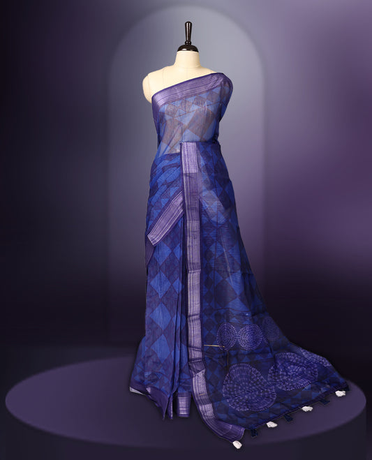 Blue saree adorned with geometric woven patterns across the body, accentuated with a subtle striped border, and a pallu featuring circular motifs with delicate tassel detailing, paired with a matching blouse.