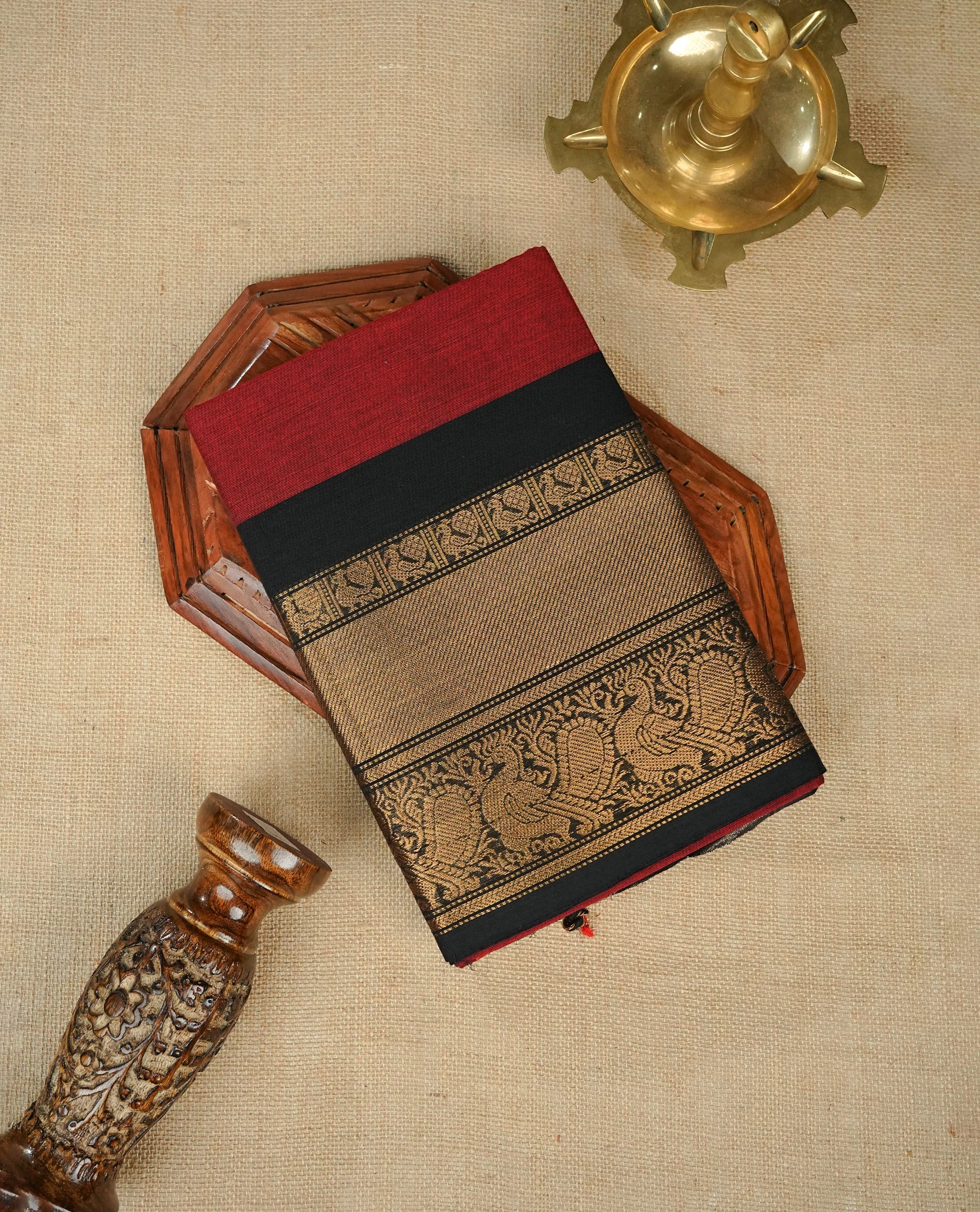 Maroon colour chettinad cotton saree featuring gold zari motifs on body, complemented by contrast black with gold zari border, comes with matching blouse piece.