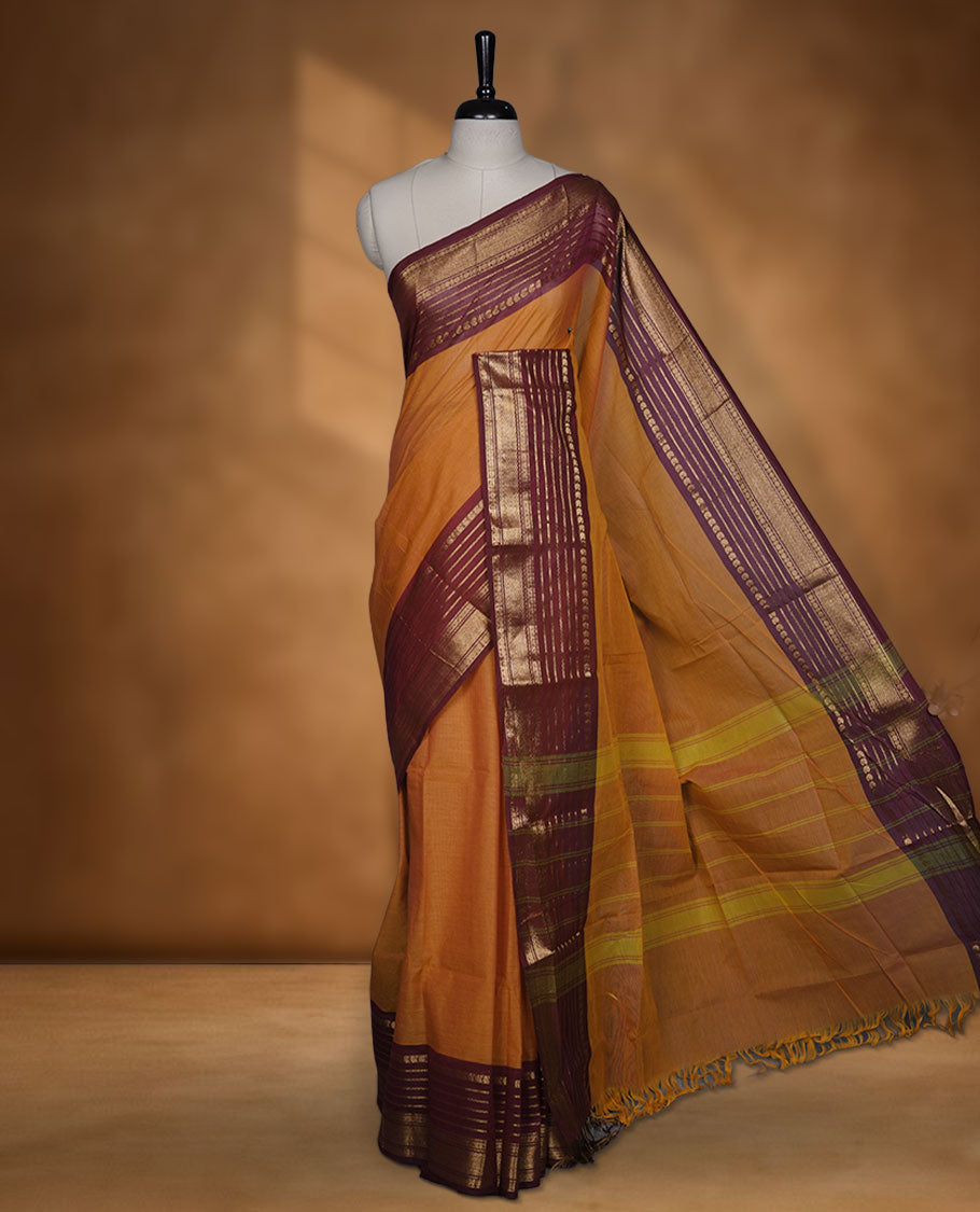 Orange colour chettinad cotton saree featuring plain body, contrast burgundy colour with traditional gold zari border paired with matching blouse.