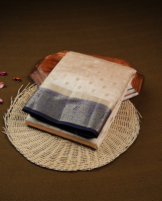 Light Gold Tussar saree featuring Gold zari buttas on body, complemented by contrast Navy Blue Colour with Gold zari border, comes with matching blouse piece.
