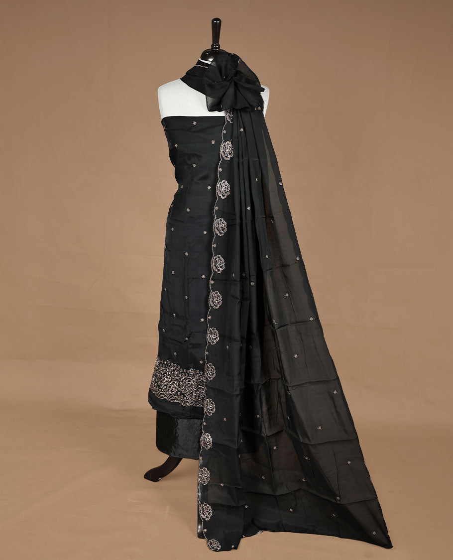 Black colour churidar material featuring floral cut beats and thread work on body, paired with matching bottom and dupatta.