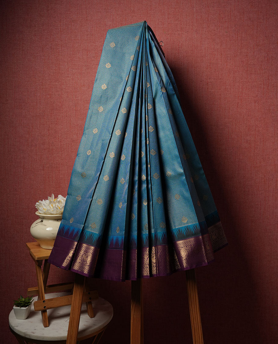 Teal colour semi silk saree highlighting gold zari check pattern  and motifs across body, featuring contrast purple colour border with gold zari pattern, comes with matching blouse .