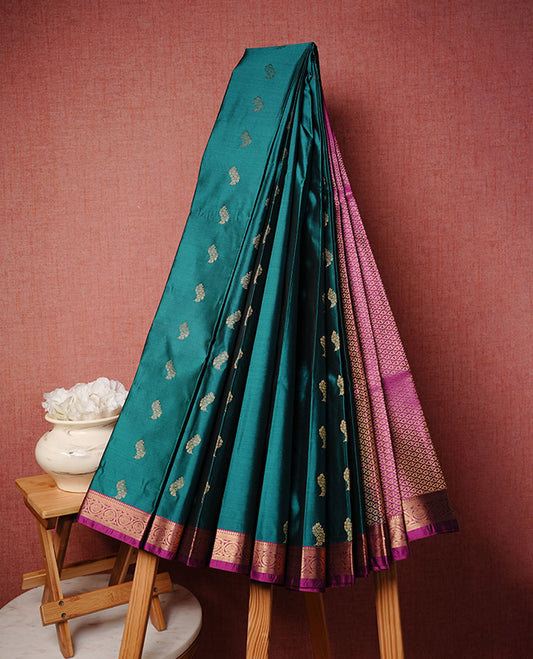 Teal colour soft silk saree featuring Gold zari  motifs on body, complemented by contrast Magenta colour with traditional border, paired with matching blouse piece.