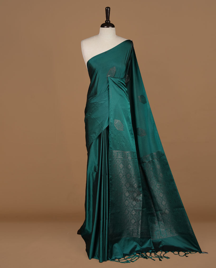 Teal green soft silk saree features a sleek borderless design with intricate antique zari motifs, flowing into a seamless self colored pallu and a matching blouse piece.