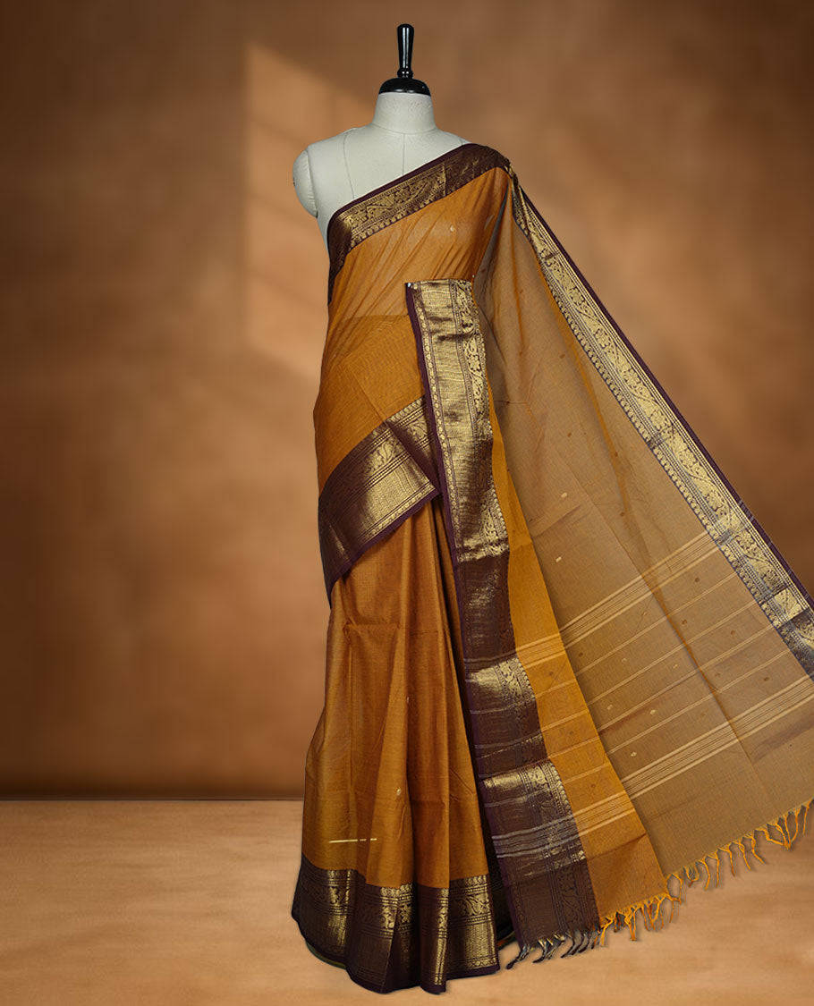 Mustard colour chettinad cotton saree featuring gold zari colour motifs on body, contrast purple colour border with gold zari border, pallu and paired with matching blouse.