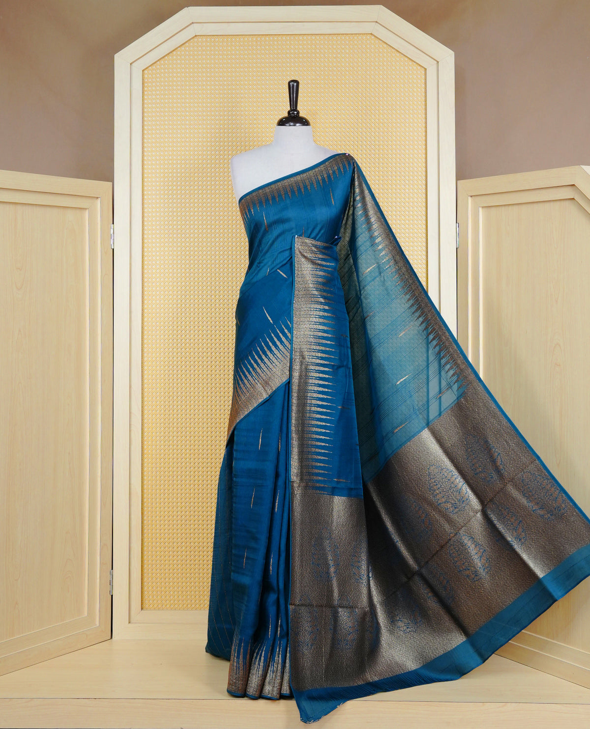 Teal colour semi banaras tussar georgette saree featuring gold zari pattern on body, finished with gold zari temple border and paired with matching blouse piece.