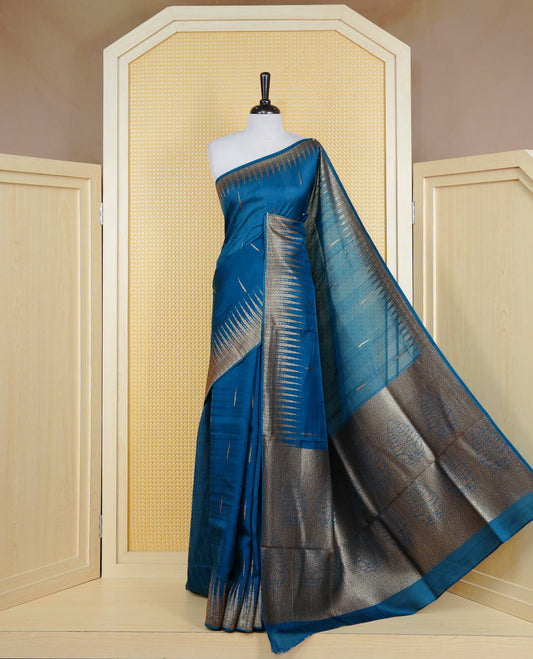 Teal colour semi banaras tussar georgette saree featuring gold zari pattern on body, finished with gold zari temple border and paired with matching blouse piece.