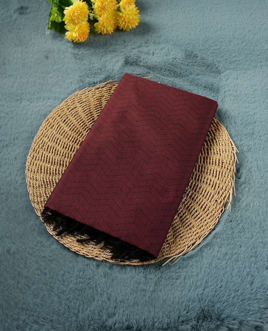 Deep Maroon colour poly cotton saree with black zigzag line pattern on the body, paired with a matching pallu featuring black chevron lines and panelled floral‑paisley design, and a coordinated all‑over floral paisley patch‑style printed blouse piece.