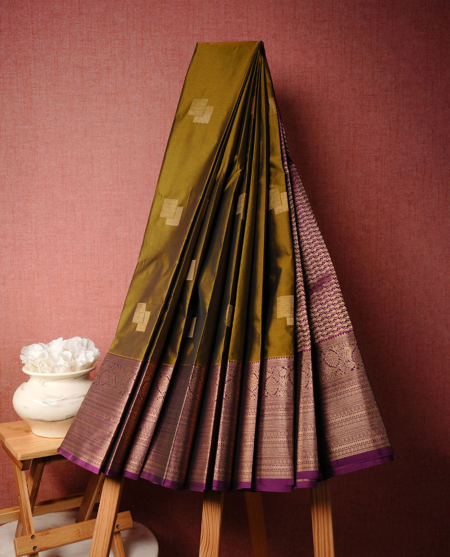 Olive colour soft silk saree featuring Gold zari motifs on body, complemented by contrast purple colour with traditional border, paired with matching blouse piece.
