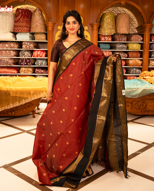 Maroon with Black colour Chettinad cotton saree featuring Gold zari strips with peacock motifs on body, complemented by contrast colour border with zari design & grand pallu, comes with matching blouse piece.