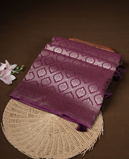 Grape colour banaras satin crepe saree featuring gold zari pattern across body, with self colour border with gold zari pattern and paired with matching blouse.