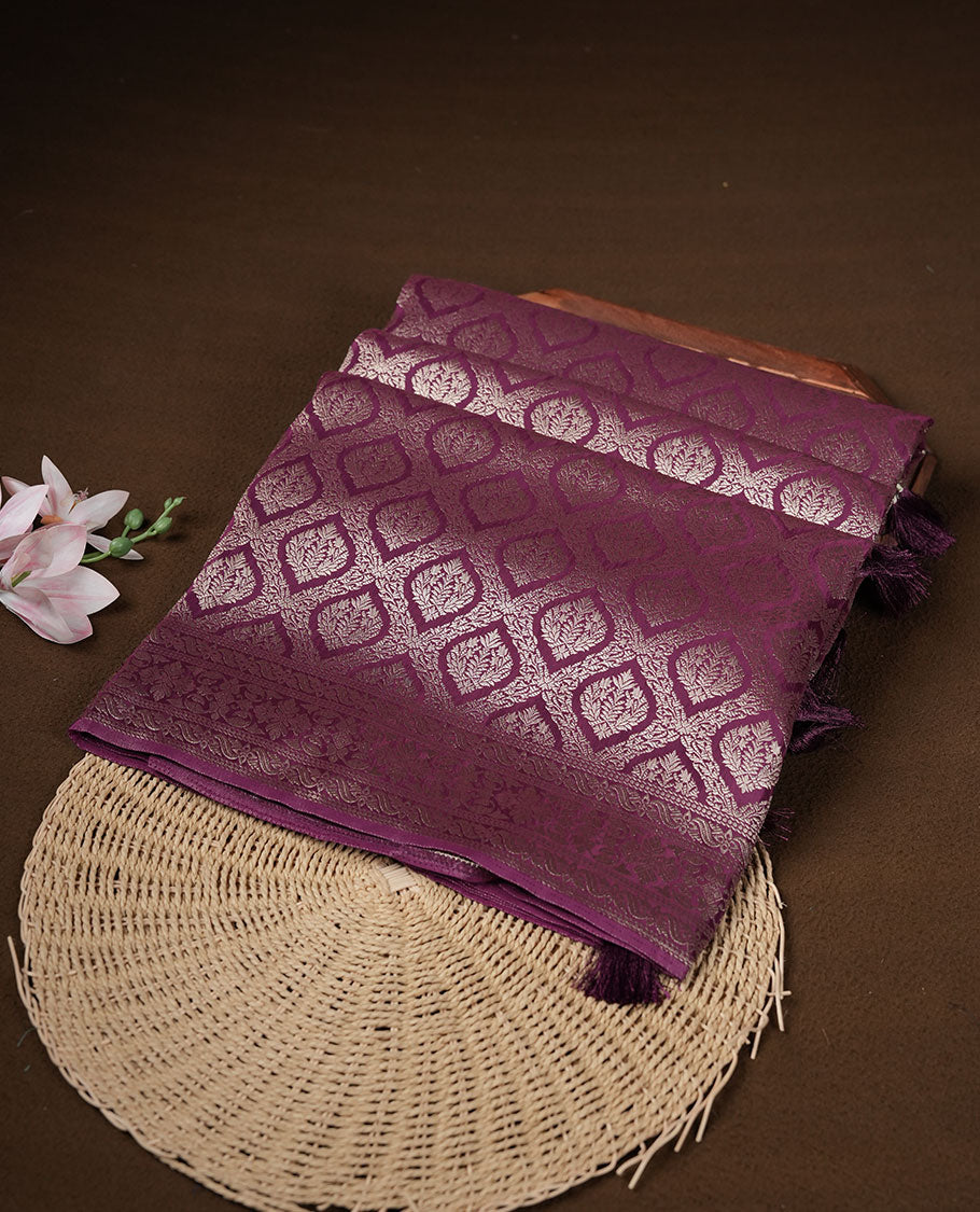 Grape colour banaras satin crepe saree featuring gold zari pattern across body, with self colour border with gold zari pattern and paired with matching blouse.