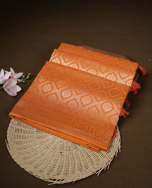 Orange colour banaras satin crepe saree featuring gold zari pattern across body, with self colour border with gold zari pattern and paired with matching blouse.