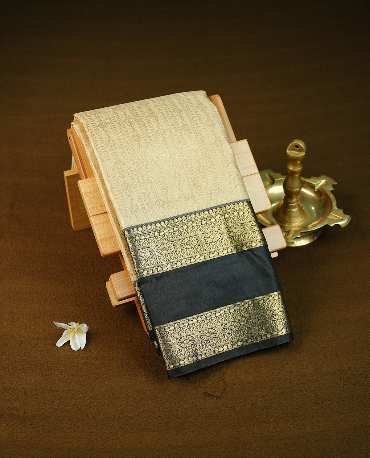 Beige colour semi wedding saree featuring gold zari Strips with motif across the body, complemented by black colour with traditional border. Comes with a matching blouse piece.