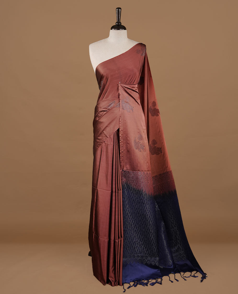 Brown colour soft silk saree features a sleek borderless design with intricate antique zari motifs, flowing into a striking contrast blue pallu and a matching blouse piece.