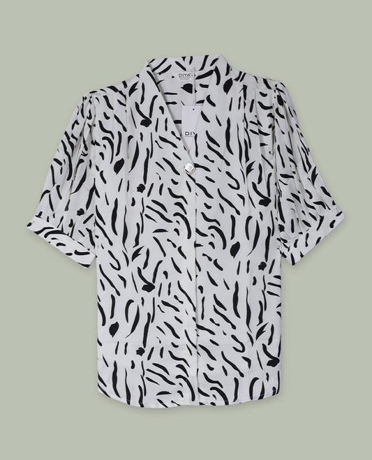 White and black abstract printed shirt top with notched lapel collar, single visible button at front, elbow-length sleeves, and softly gathered shoulders.