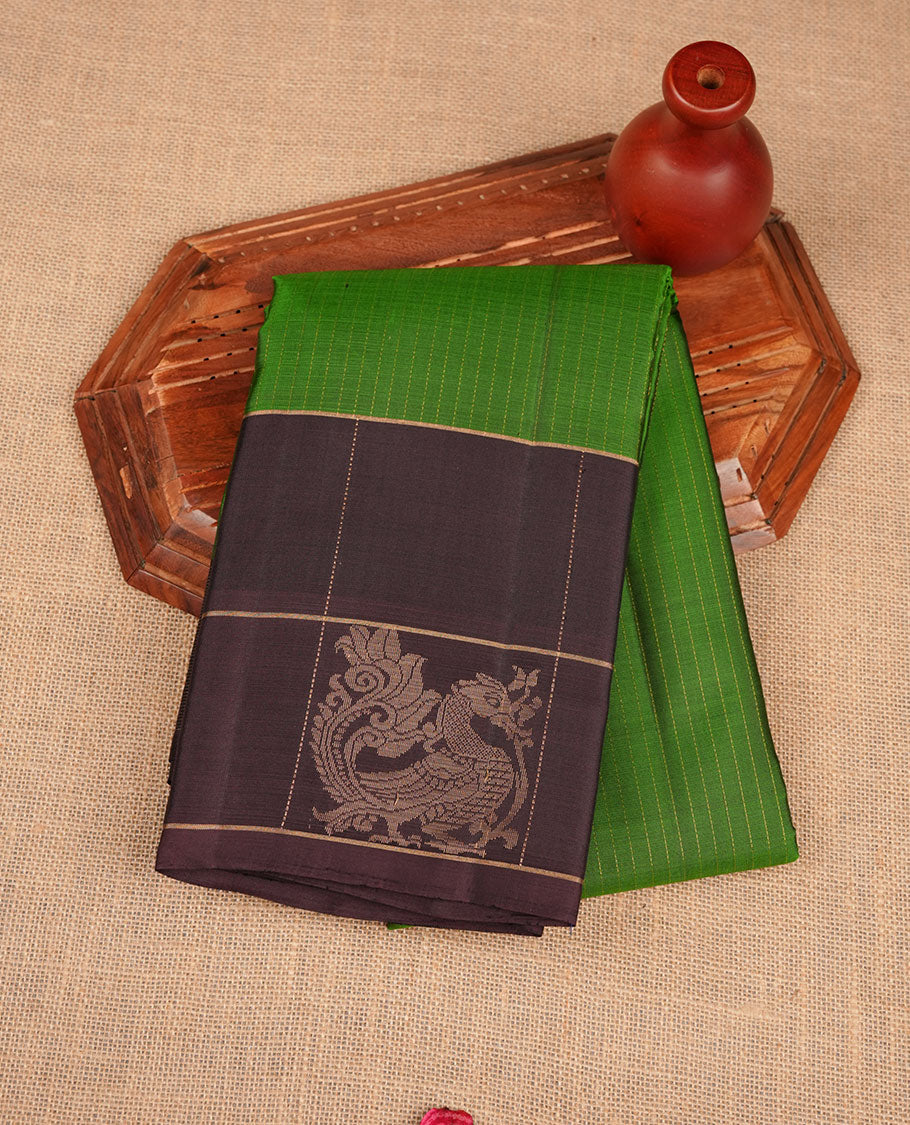 Green colour soft silk saree featuring elegant gold zari stripes across the body, complemented by a contrast burgundy with peacock buttas on border, and paired with a matching blouse piece.