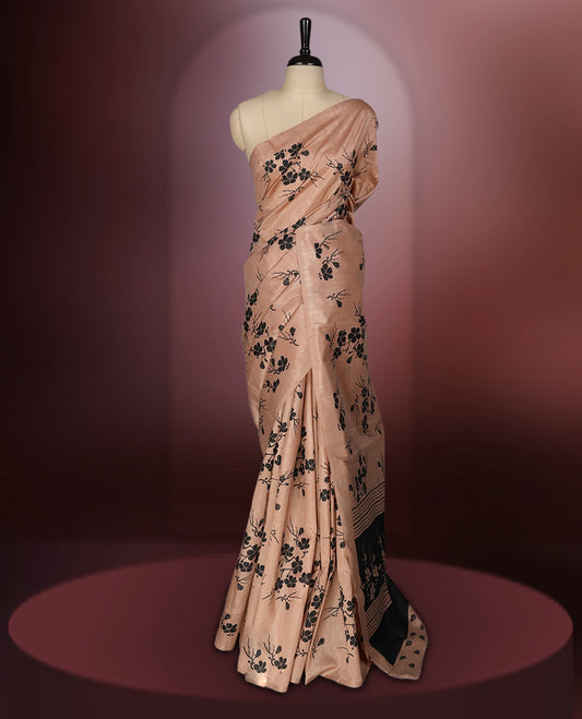 Pastel peach colour saree with delicate black floral prints spread across the body, The black pallu features coordinated floral motifs and stripes, Finished with a sleek border and paired with a matching blouse.