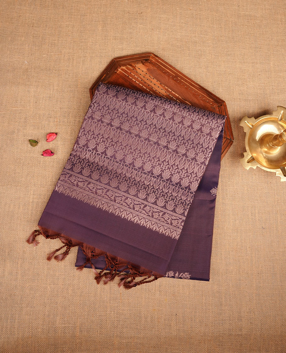 Plum purple colour soft silk saree featuring gold zari motifs on body, complemented by self colour with traditional border with tassel at pallu, paired with matching blouse piece.