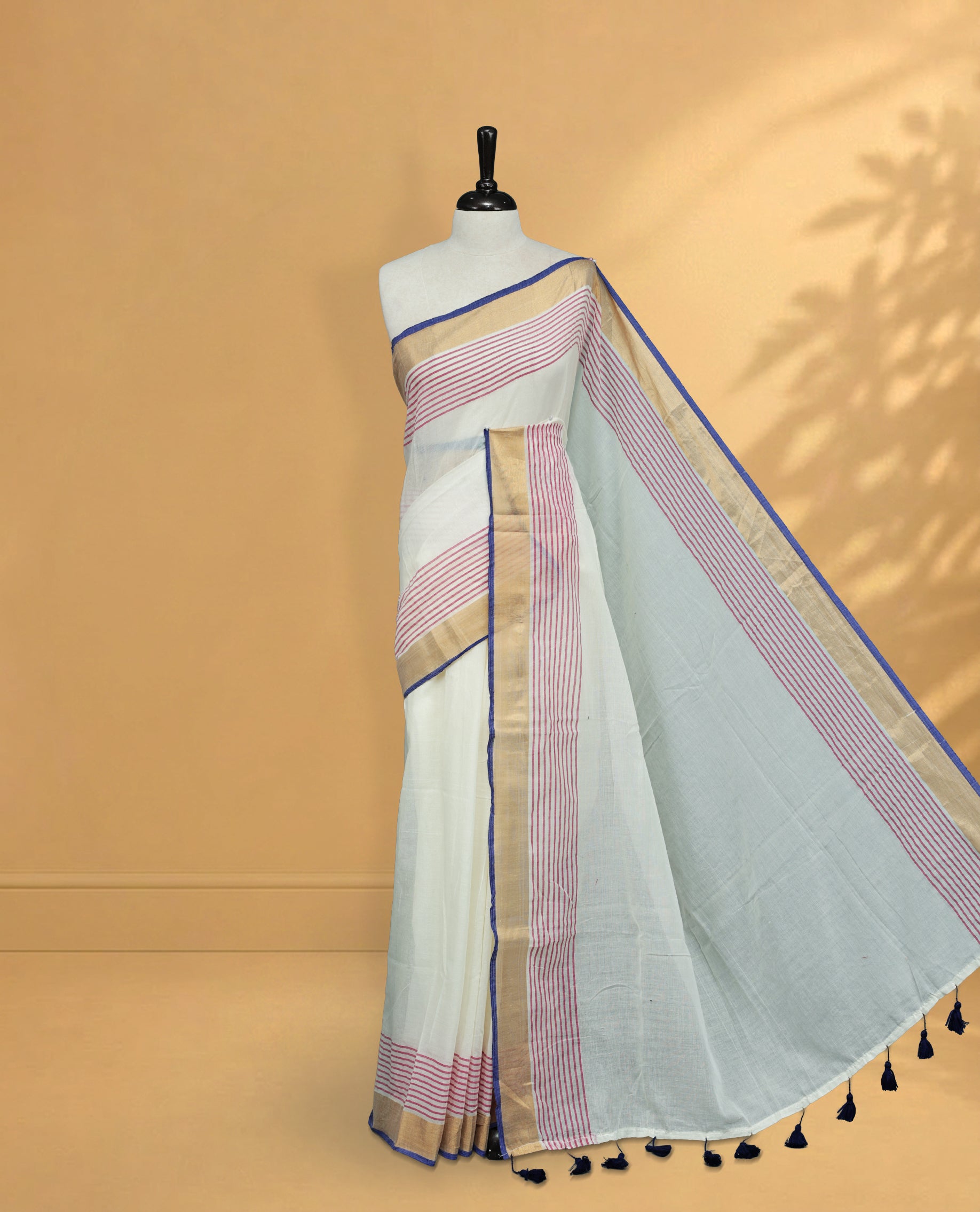 Off White Colour Mul Cotton Saree featuring Elegant Plain Body, Contrast Gold, Pink & blue Border and Tassels Onam inspired charm.