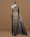 Greyish green soft silk saree features a sleek borderless design with intricate antique zari motifs, flowing into a seamless self colored pallu and a matching blouse piece.