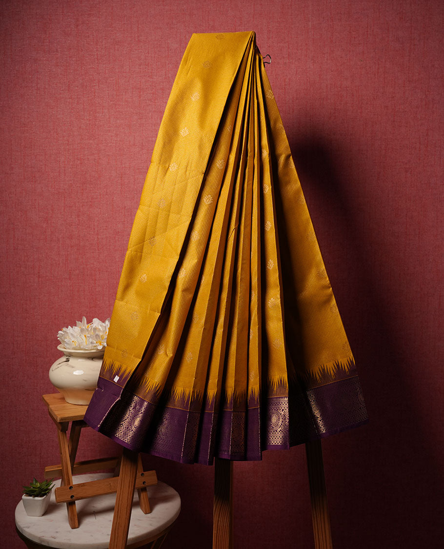 Mustard colour semi silk saree highlighting gold zari check pattern  and motifs across body, featuring contrast purple colour border with gold zari pattern, comes with matching blouse .