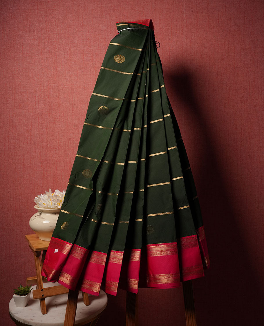 Dark green colour semi silk saree highlighting gold zari stripes and motifs across body, featuring contrast Pink colour border with gold zari pattern, comes with matching blouse.