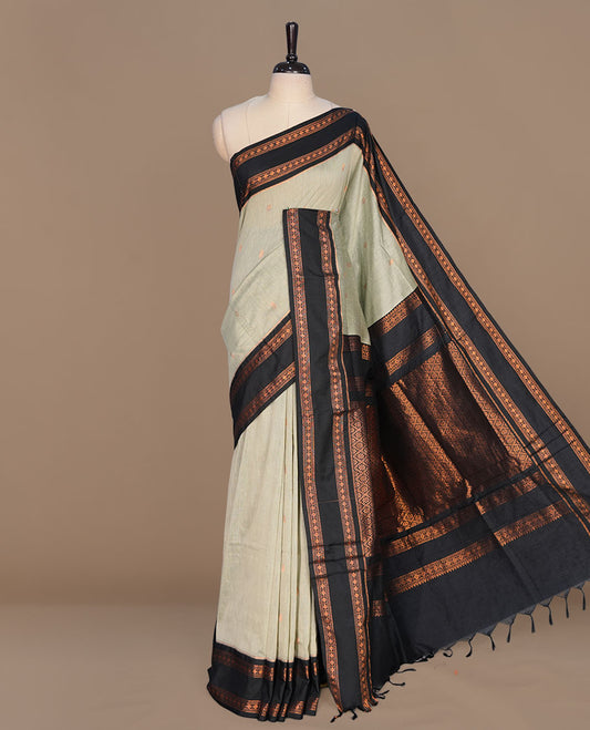 Mustard colour kalyani cotton saree featuring gold zari motifs on body, complemented by contrast green color with copper zari pattern border , paired with matching blouse piece.