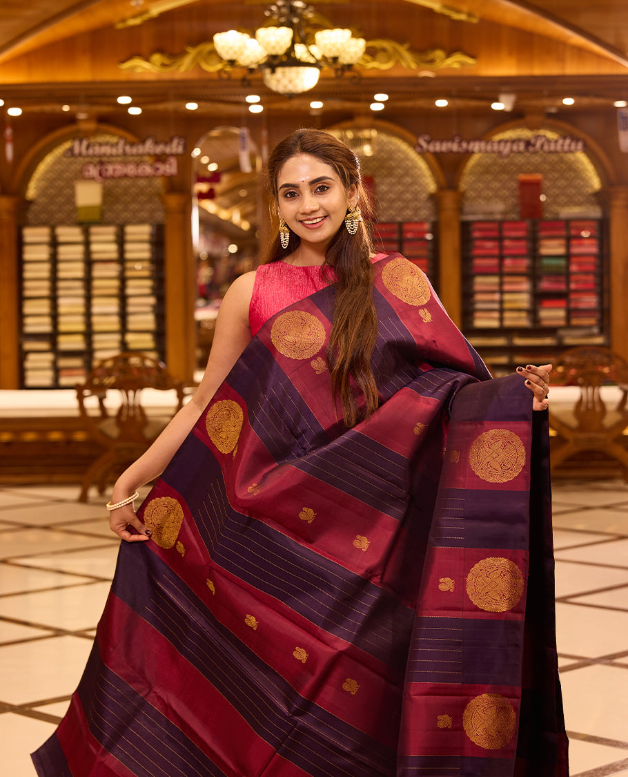 Graceful maroon and deep indigo colour kancheepuram silk saree adorned with classic gold zari polka motifs and elegant horizontal weaving, finished with a striking pallu and perfectly complemented by a blouse