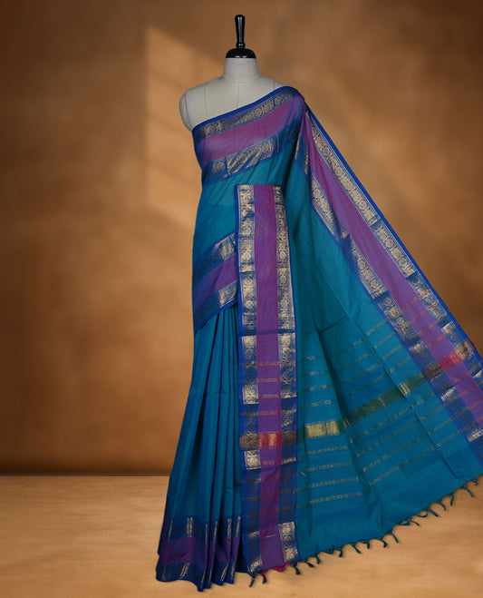 Aqua lake colour chettinad cotton saree featuring elegant plain body highlighting contrast magenta and blue colour with gold zari Peacock border, pallu and paired with matching blouse piece.