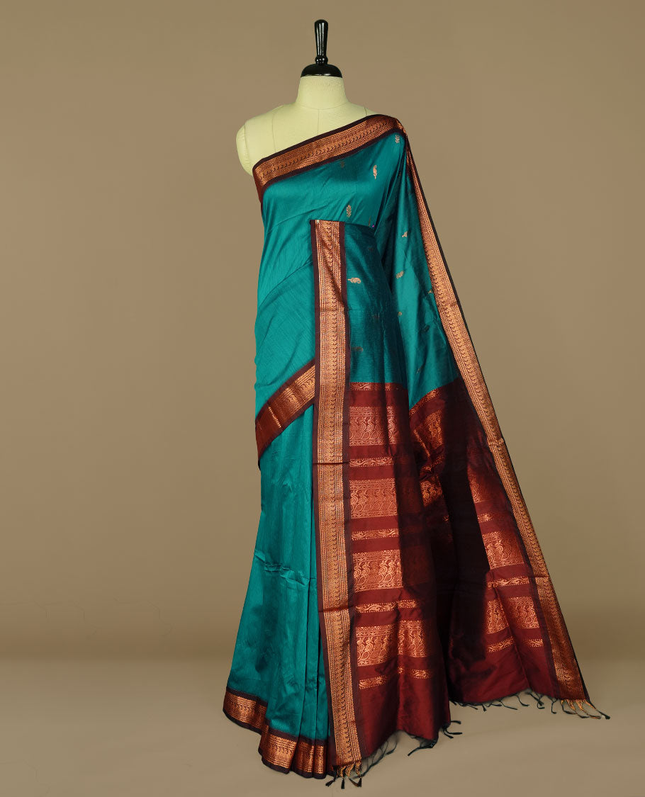 Peacock green colour kalyani cotton saree featuring gold zari motifs on body, complemented by Maroon colour with Antique zari border, paired with matching blouse piece.
